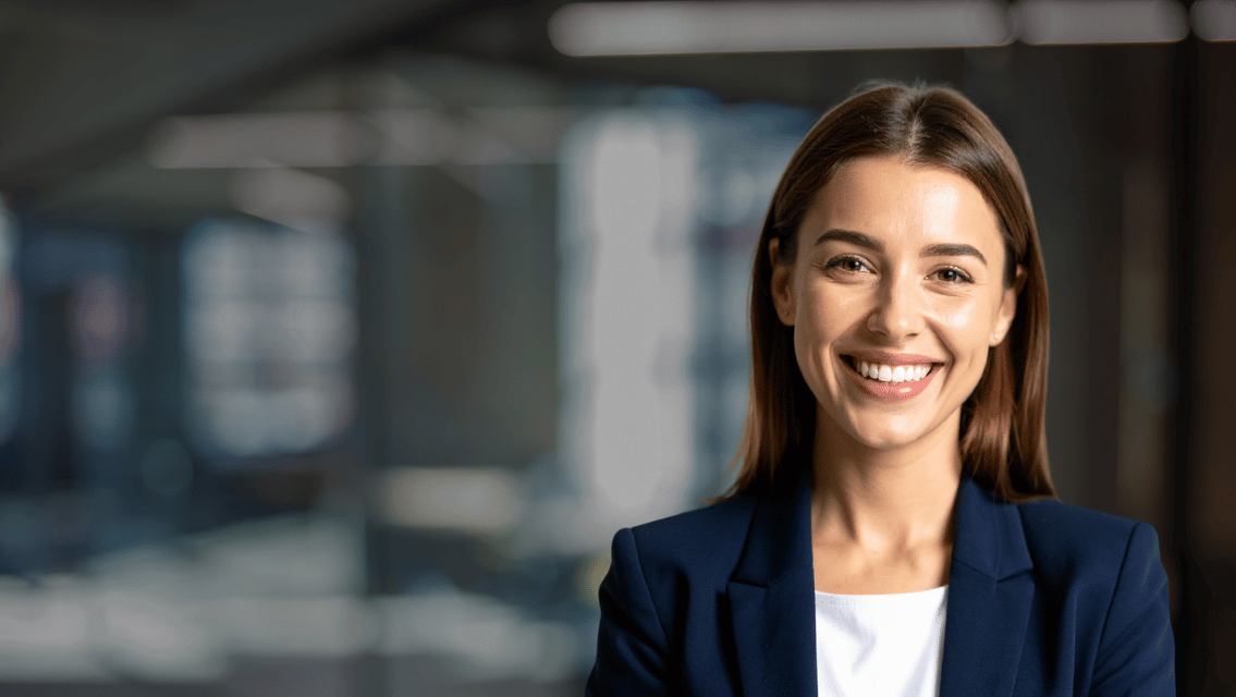 Smiling businesswoman in a navy blazer standing in a modern office.