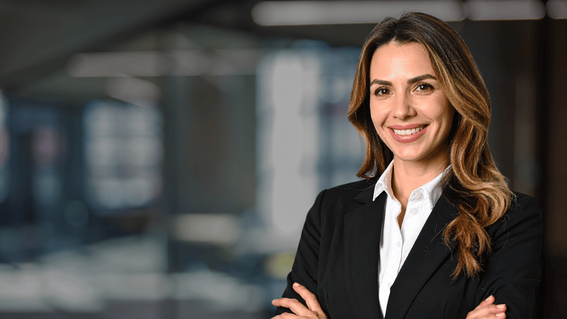 Smiling woman in a black suit in a modern office environment.
